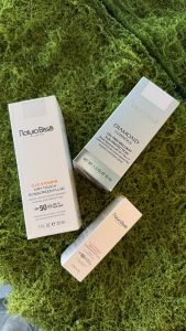 Natura Bissé C+C Vitamin SPF 50 Dry Touch Sunscreen Fluid i reseformat på grön mossa.